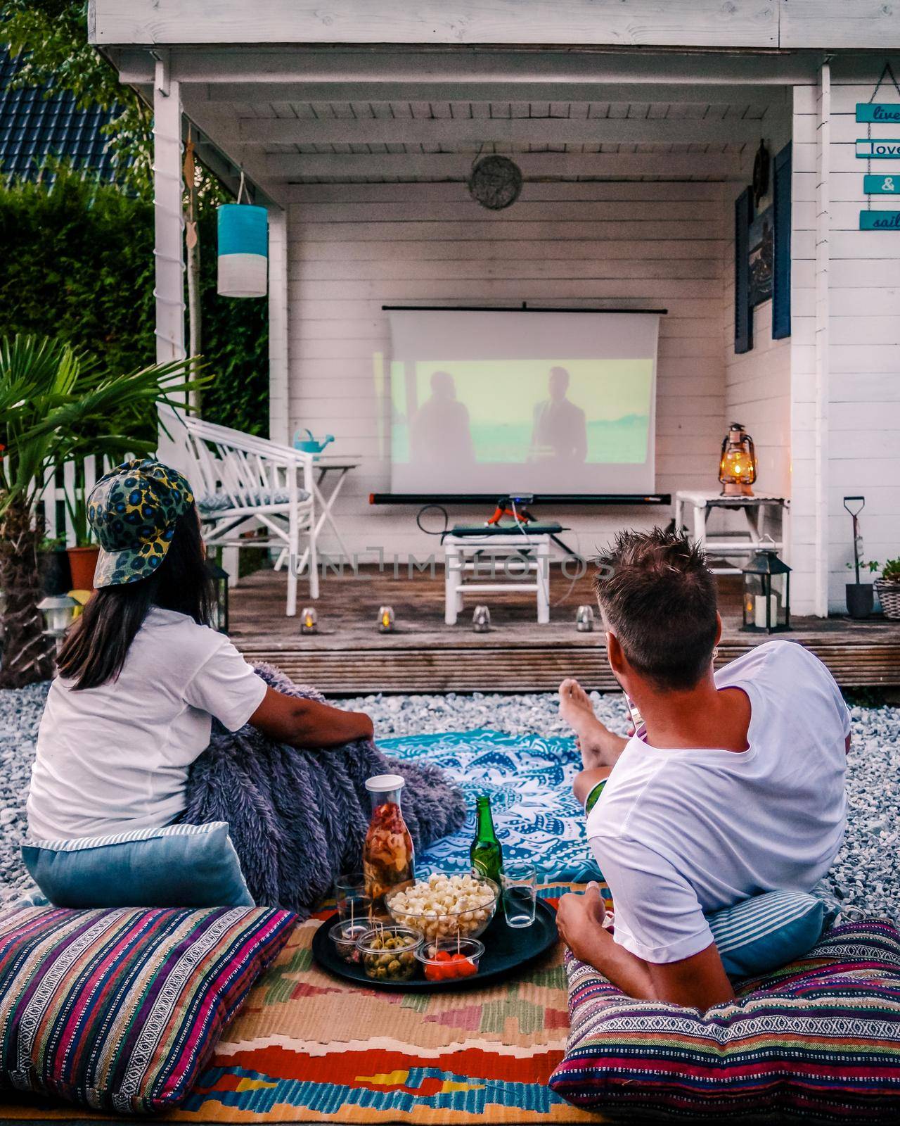 couple looking movie in garden at night , people looking movie in the garden, garden cinema night at home by fokkebok