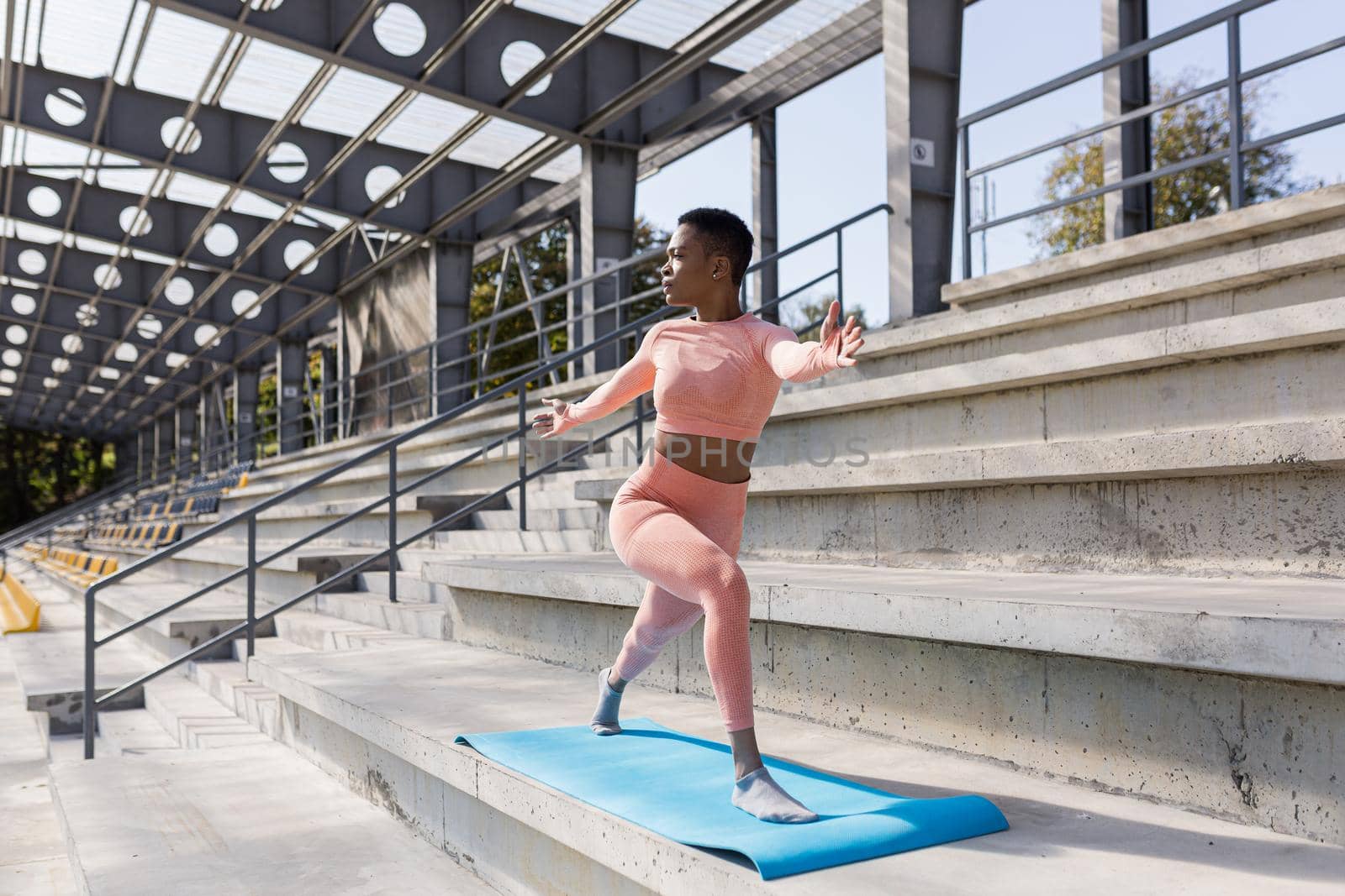 African American woman doing yoga near the stadium in the morning, active lifestyle performs fitness exercises