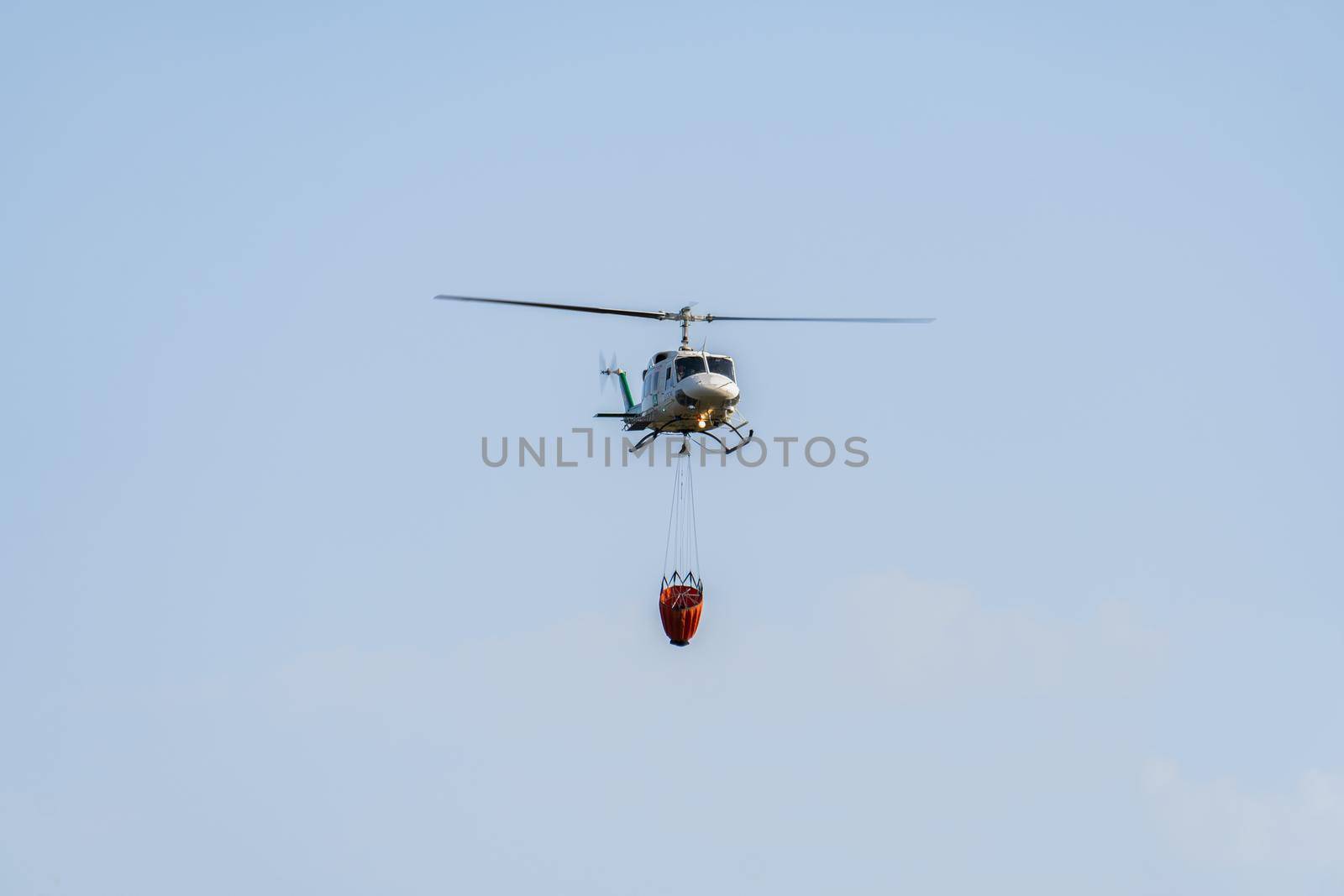 firefighting helicopter in mid-flight dropping water bag on flames