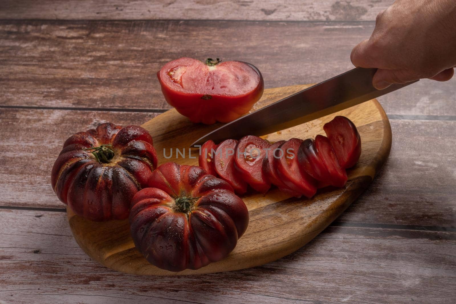 woman's hand with knife cutting tomatoes on a board by joseantona