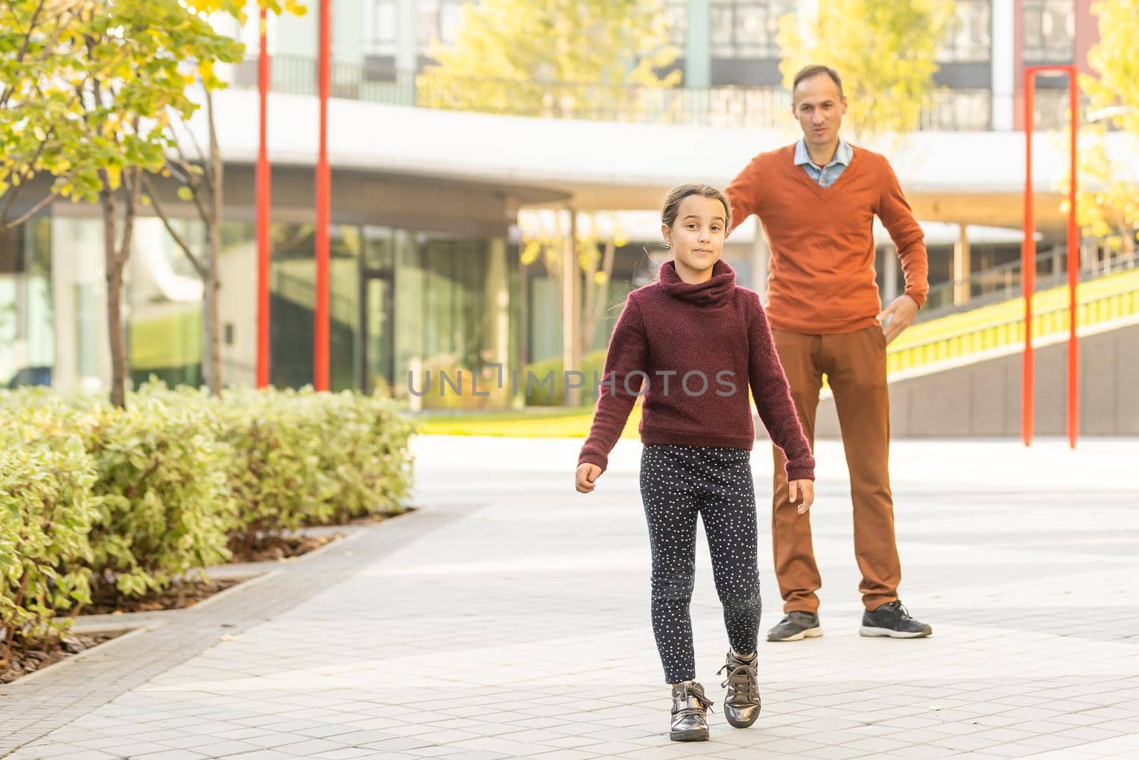 Happy father and daughter walking together in park on an autumns day.