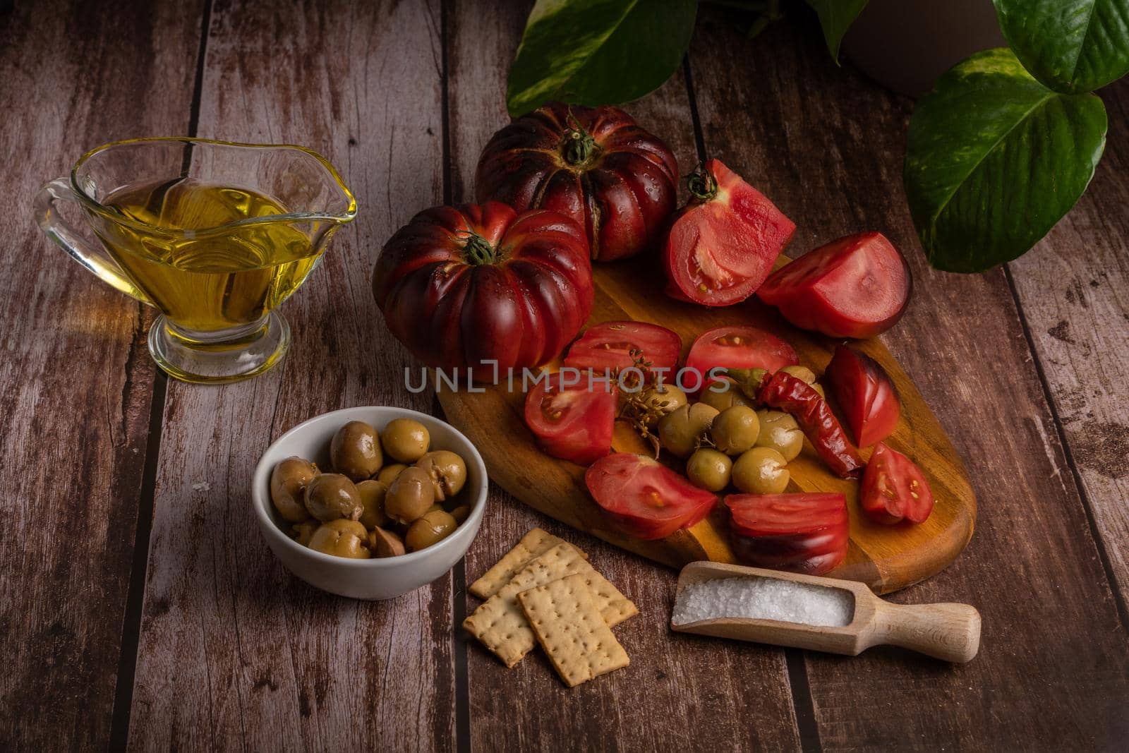 organic moorish tomatoes with oil, salt and olives on a wooden table, mediterranean diet