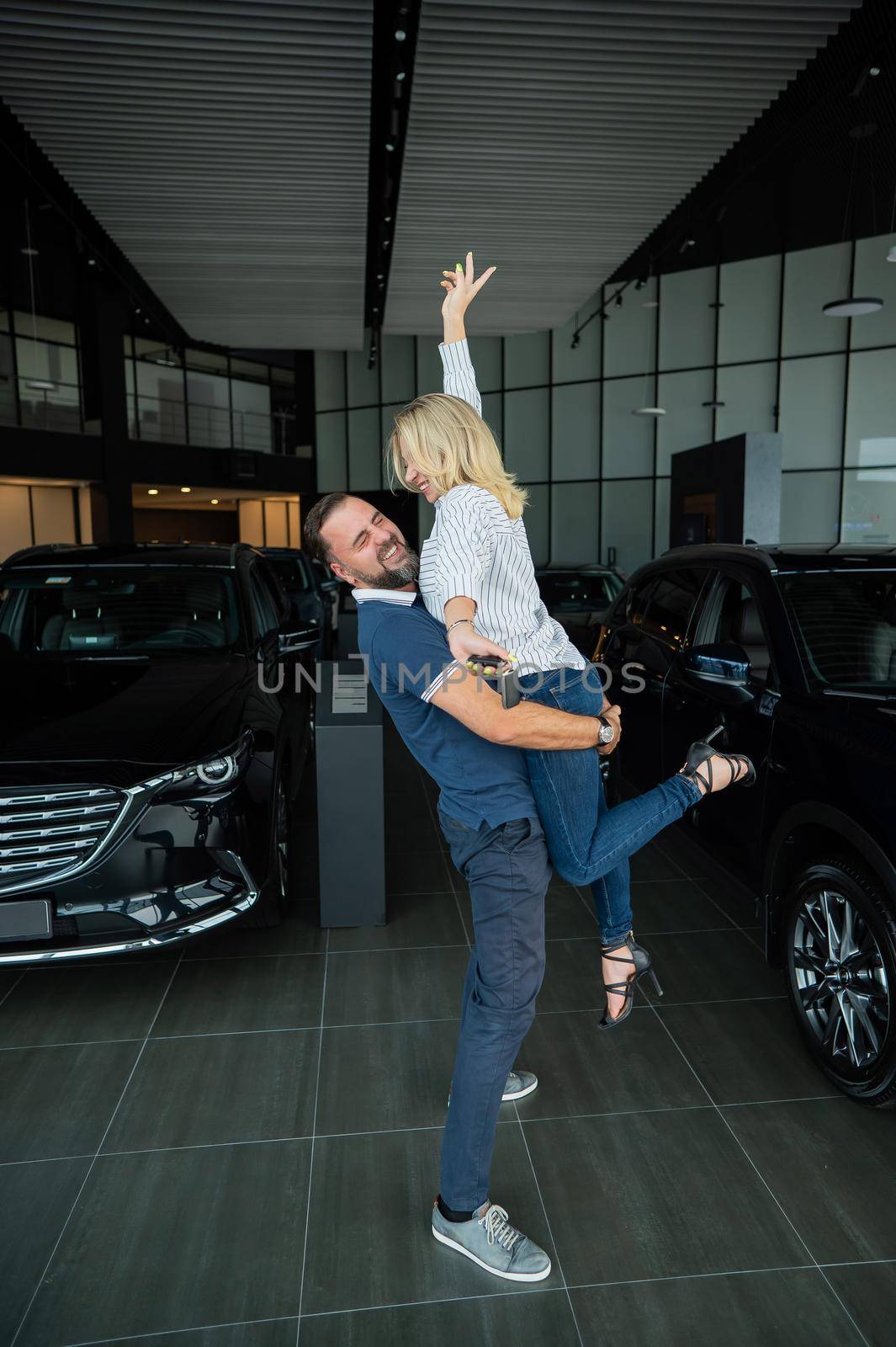 Happy caucasian couple hugging while buying a new car in a car dealership