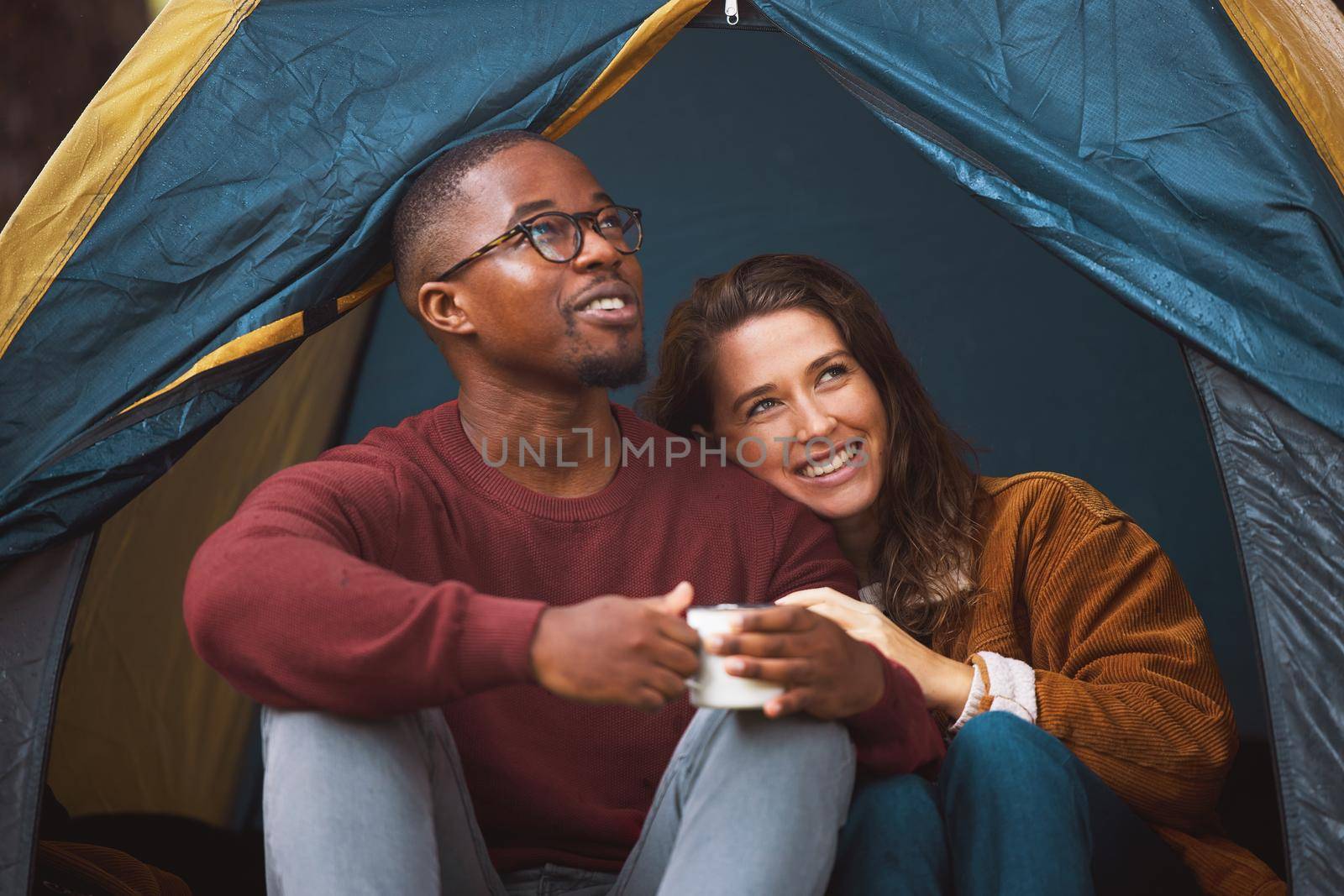 Nothing says romance like a tent, chirping birds and bae. a young couple drinking coffee while sitting in their tent. by YuriArcurs