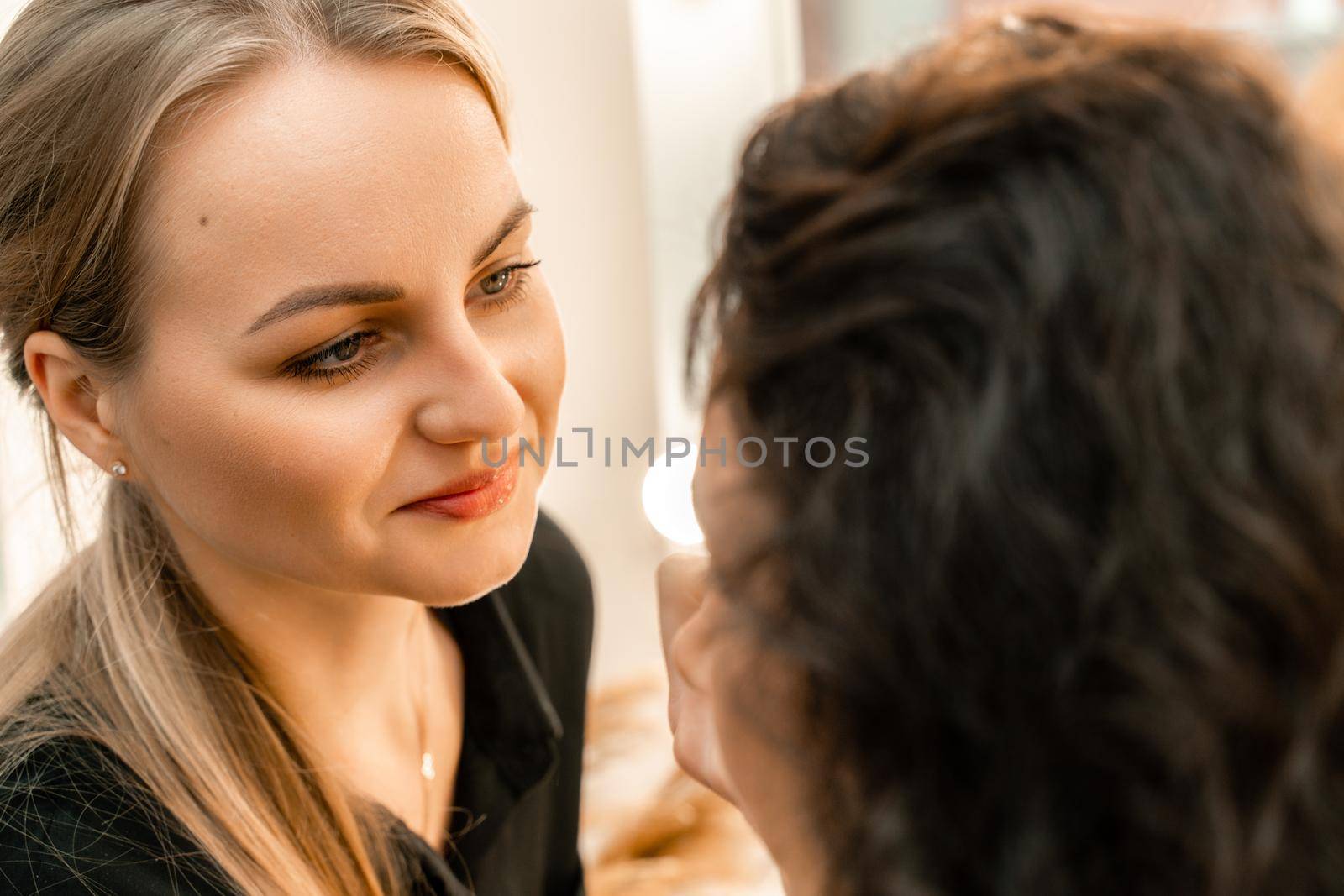 Make-up artist makes a professional make-up of a young woman in the studio. by Matiunina