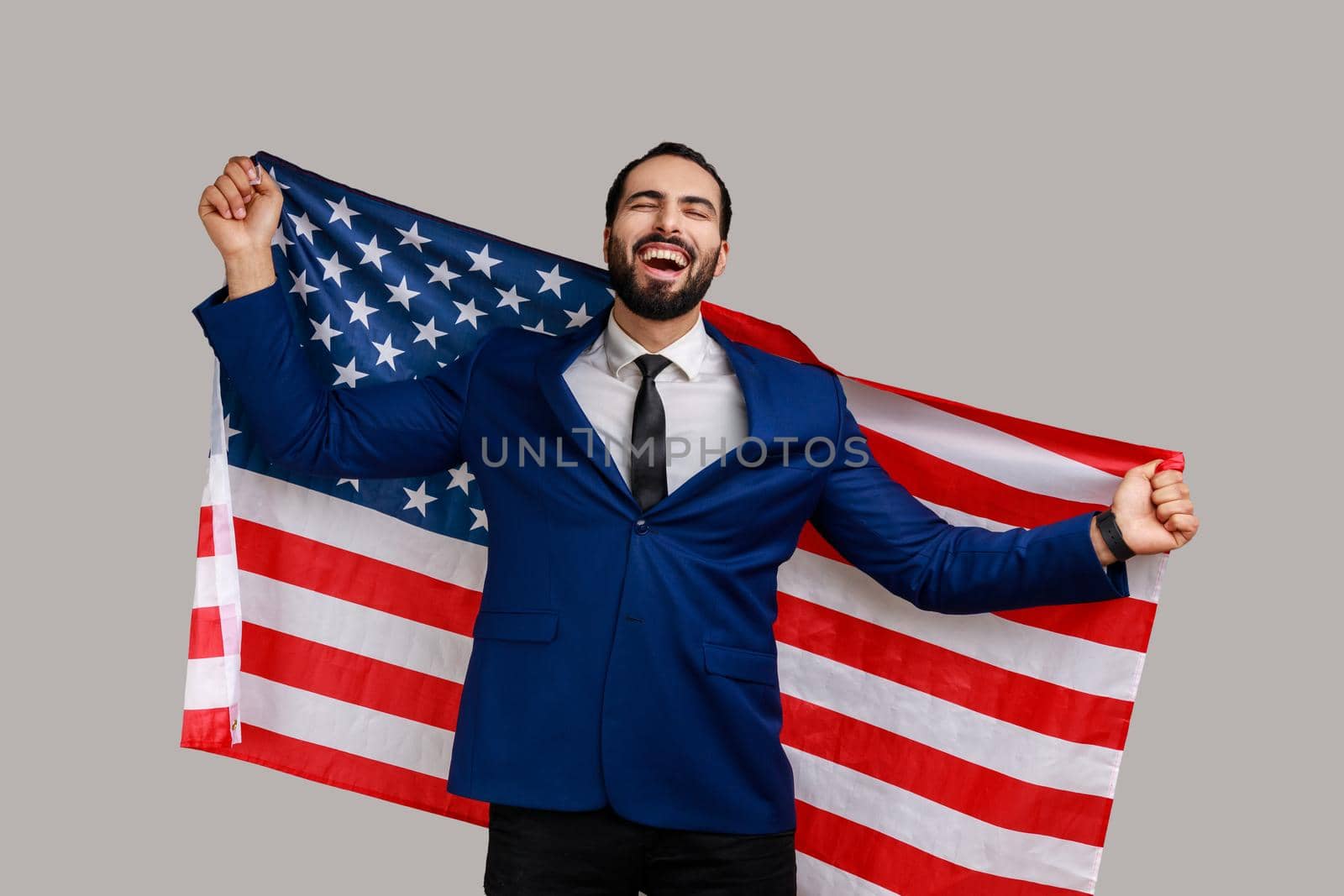 Excited man holding USA flag and looking at camera with rejoice look, celebrating national holiday. by Khosro1
