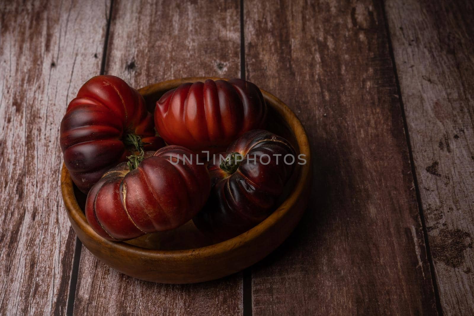 group of moorish tomatoes in a wooden bowl isolated on a wooden table