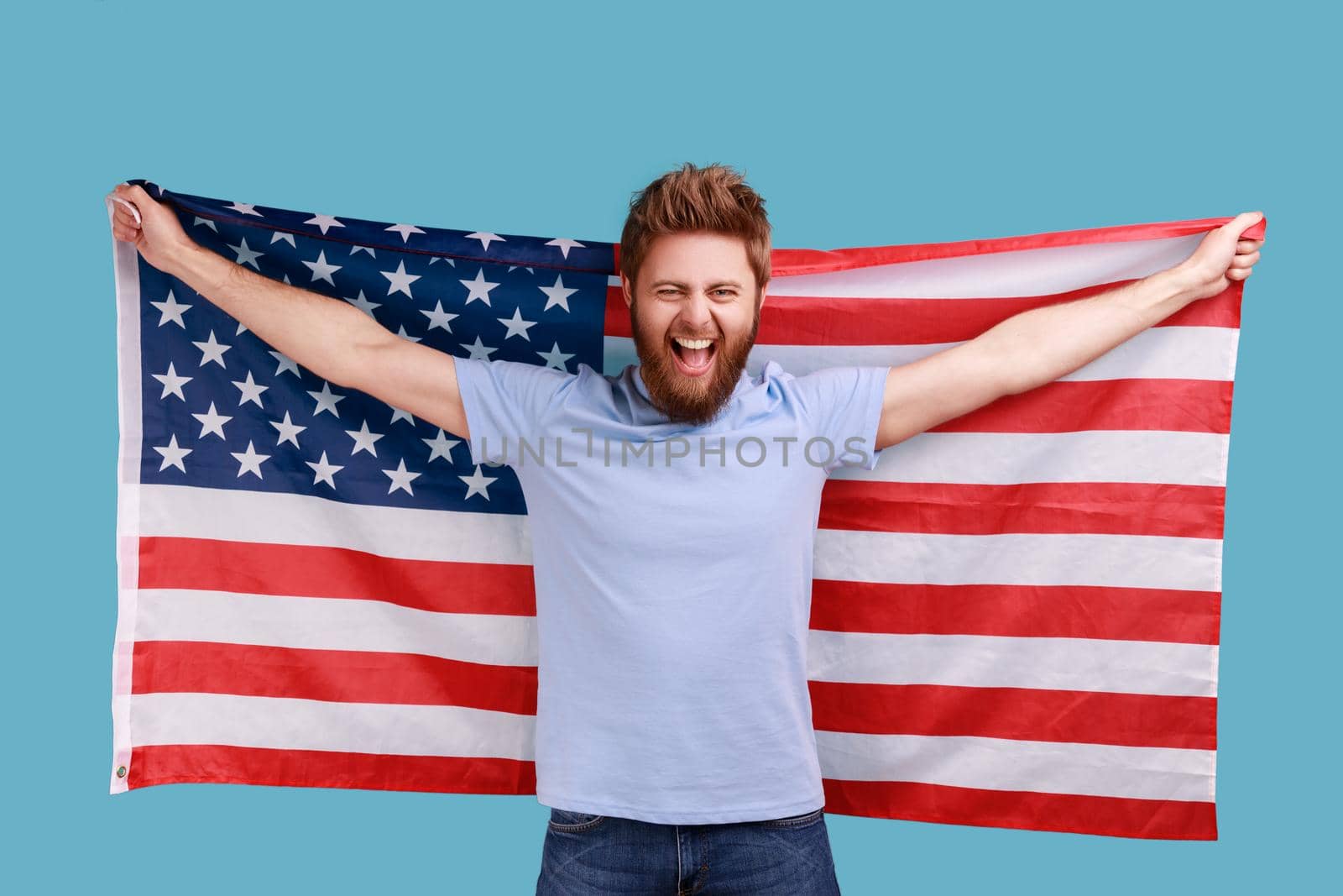 Man holding USA flag and looking at camera with rejoicing look, celebrating national holiday. by Khosro1