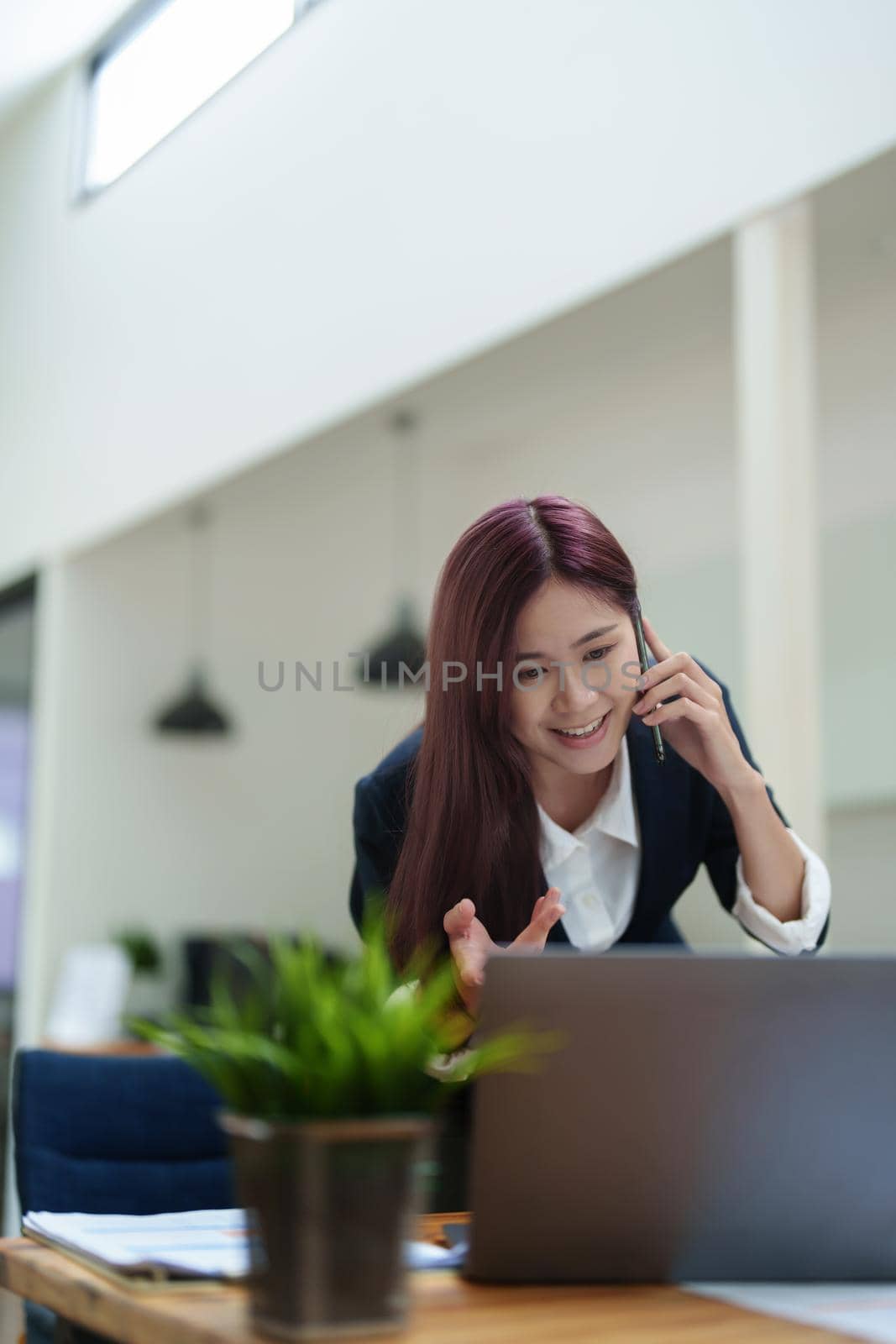 Asian businesswoman using the phone to contact a business partner by Manastrong