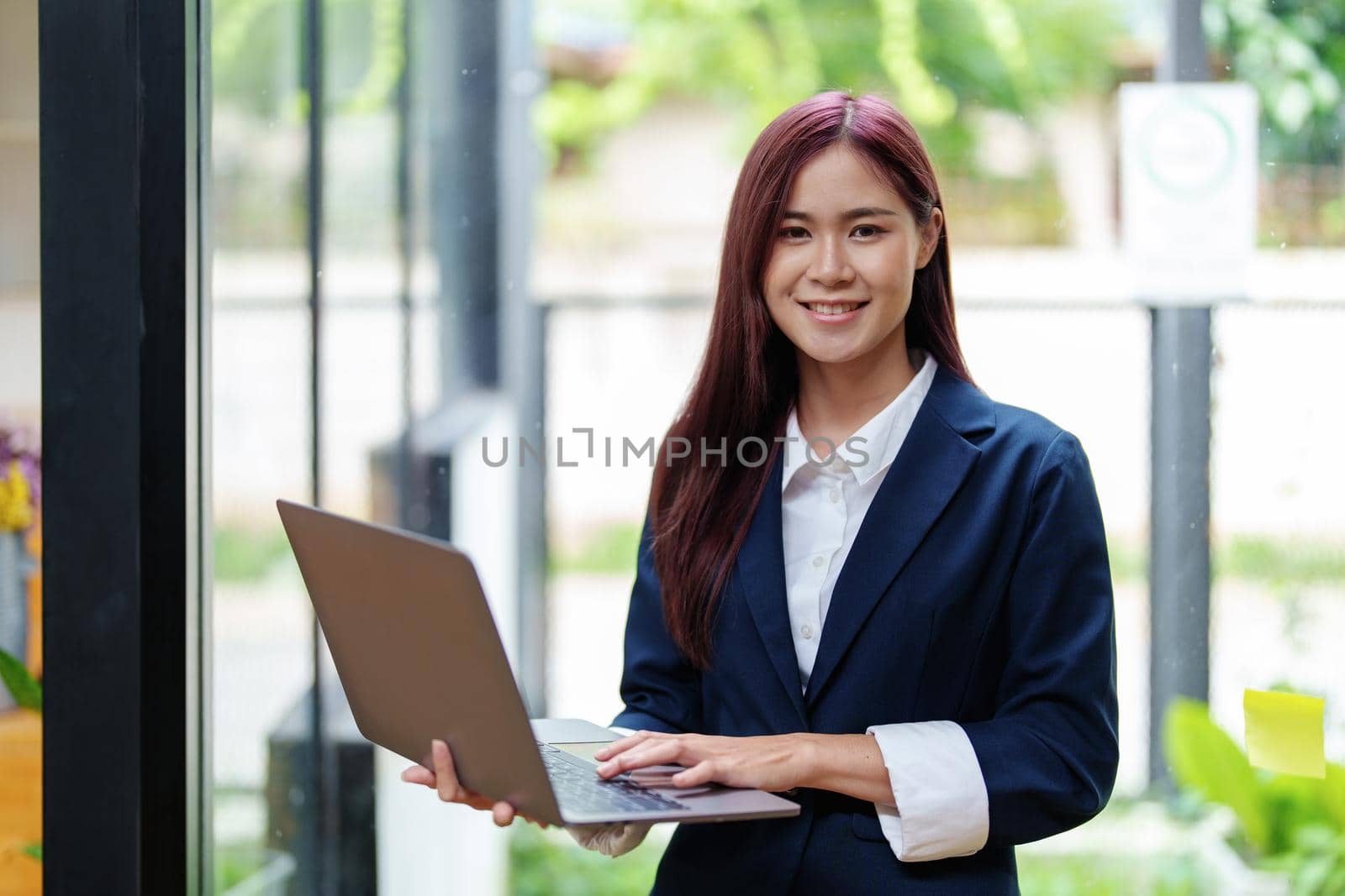 Portrait of a smiling Asian businesswoman holding a computer.