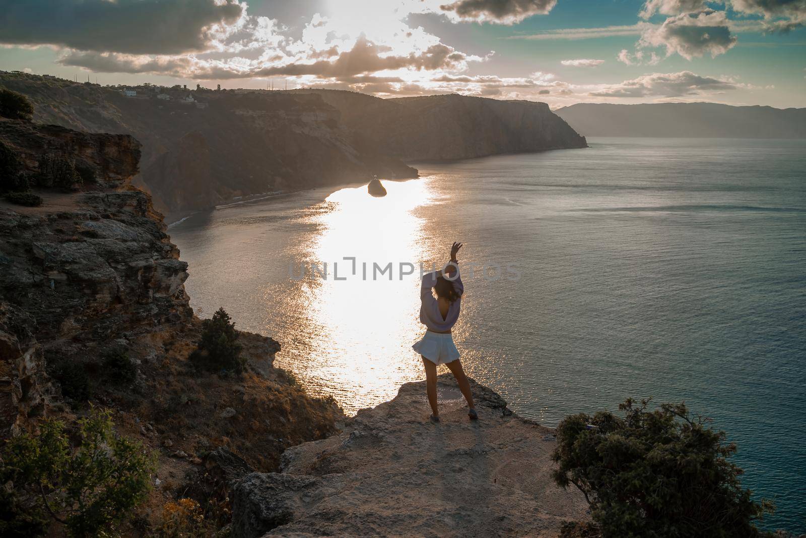 Free girl with open arms at sunset over the sea, sun over clouds, sunset in the mountains, golden hour, silhouette of a woman at sunset on the mountain by Matiunina