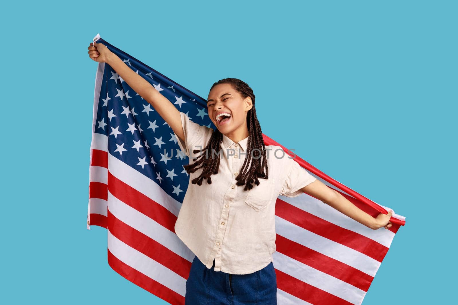 Woman with dreadlocks holding USA flag over shoulders and keeps eyes closed and smiling happily. by Khosro1