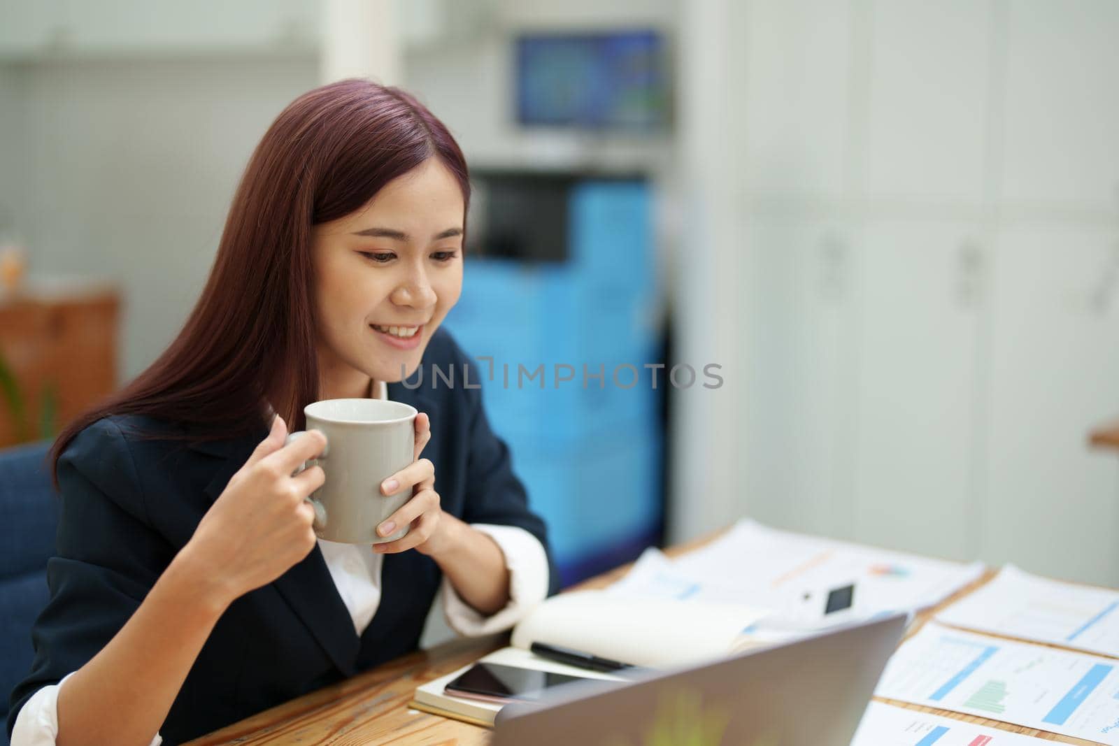 Asian businesswoman taking a coffee break while using a computer.