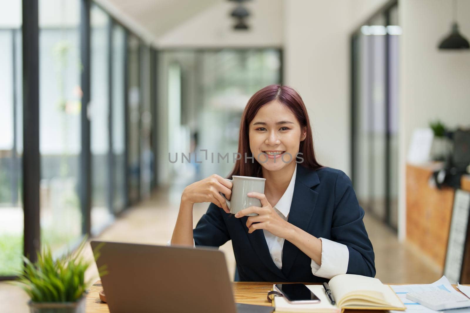 Asian businesswoman taking a coffee break while using a computer.