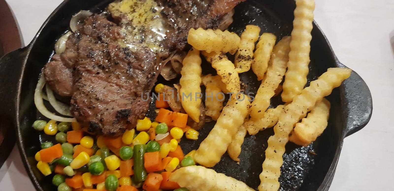 The best food in the world beef steak along with fried potatoes with delicious mushroom sauce and salad and spaghetti plated in beautiful black plate