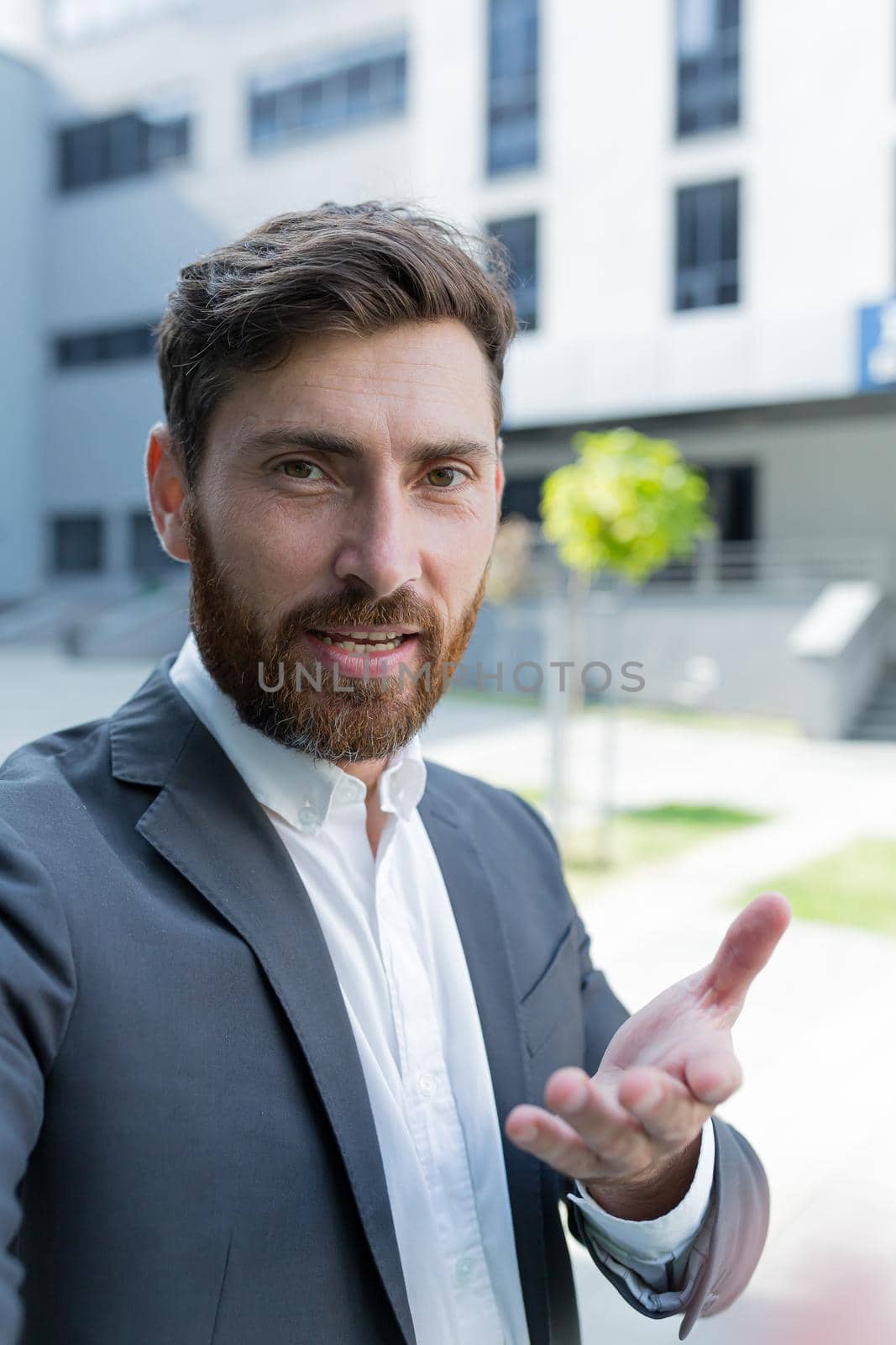 vertical view smartphone camera Caucasian bearded businessman speaks on phone using a front camera on a video call. employee business man talking on webcam. Conversation of an office worker in suit