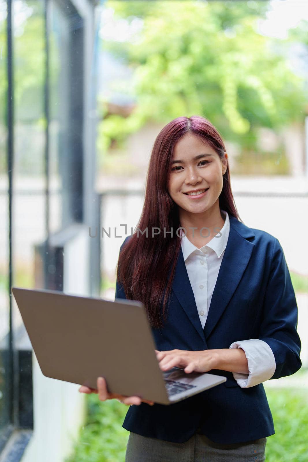 Portrait of a smiling Asian businesswoman holding a computer by Manastrong