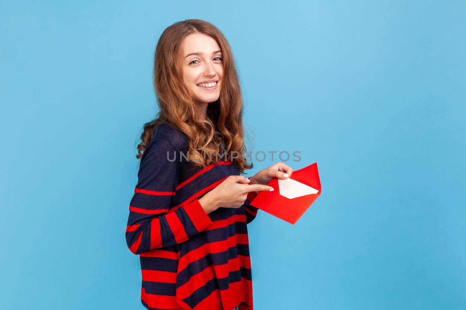 Woman pointing letter in red envelope, holding greeting card and smiling joyfully. by Khosro1