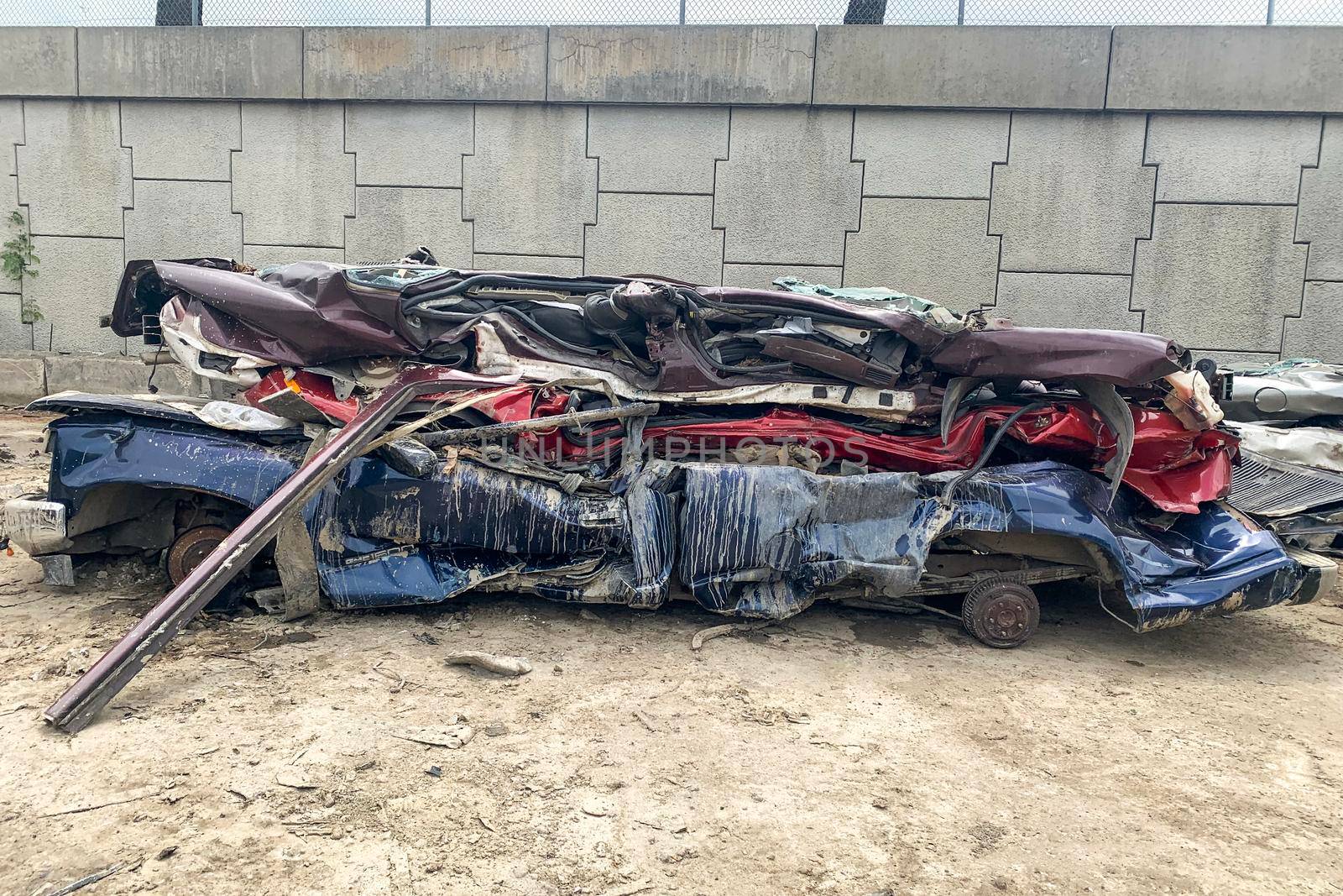 A pile of compressed cars going to be shredded, crushed junk vehicles on scrapyard