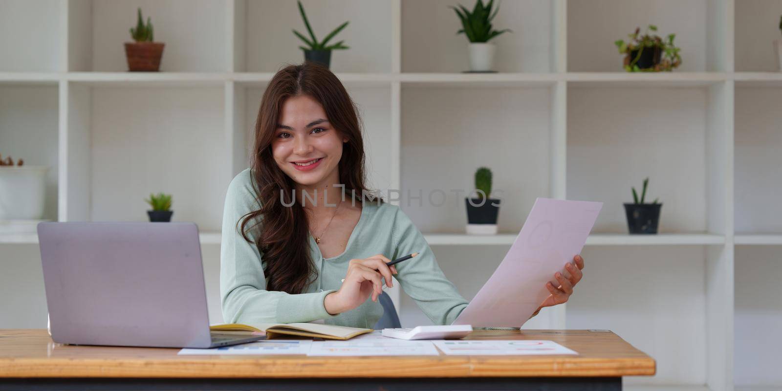 Business Woman analyzes company's financial system and paperwork on desk.