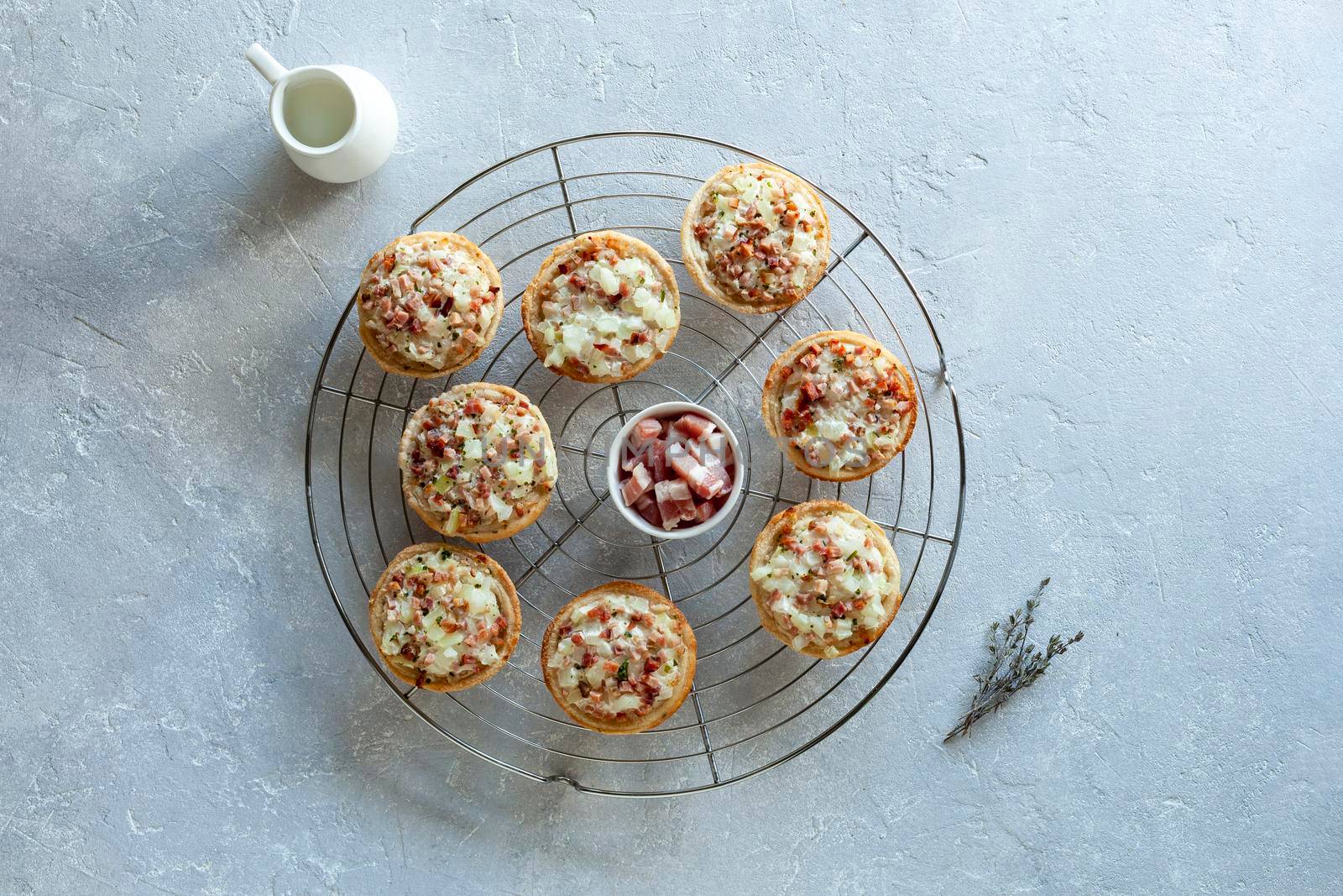 mini portions of flammekueche, or tarte flambee, french and german speciality, on the metal round cooling grid, top view