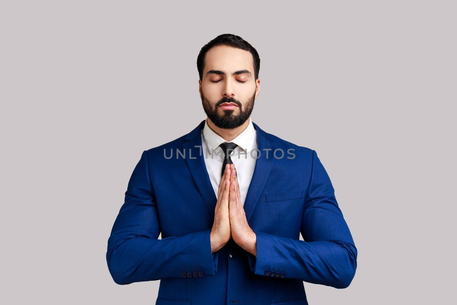 Calm handsome bearded businessman standing in yoga pose and try to relaxing, keeps palms together. by Khosro1