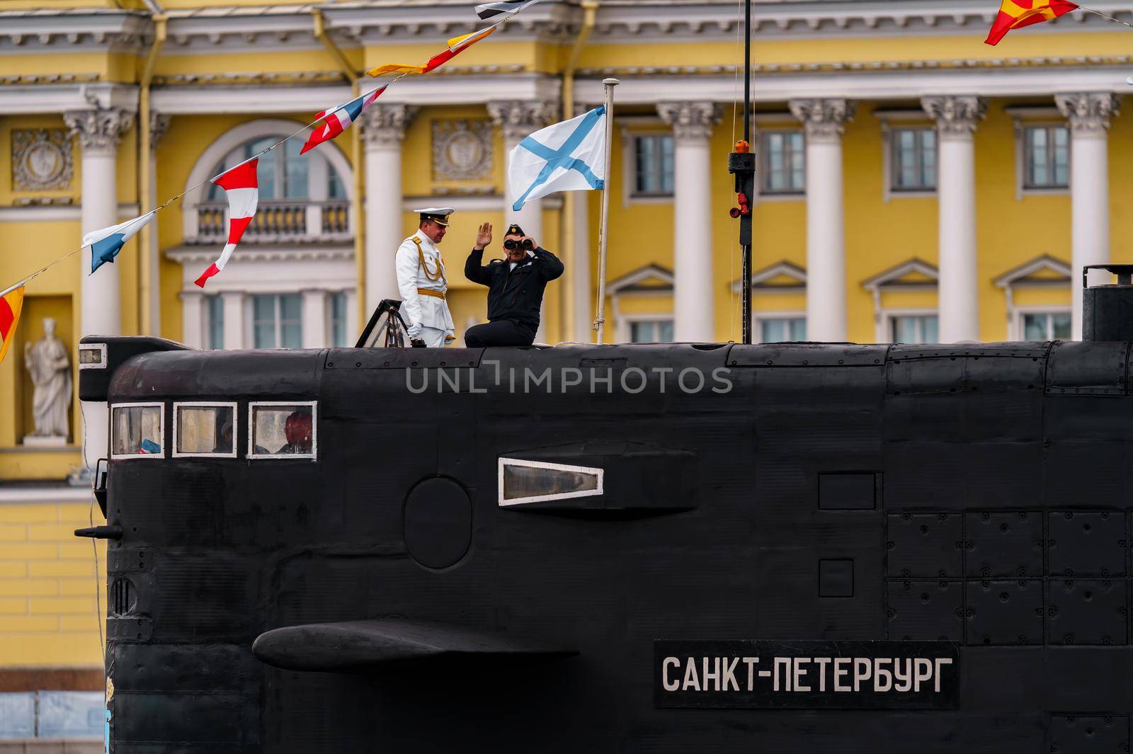 Russia, St. Petersburg, 31 July 2022: The commander of a submarine standing in the center of the city looks through binoculars, he is dressed in a festive white uniform, celebration of the day of Navy. High quality photo