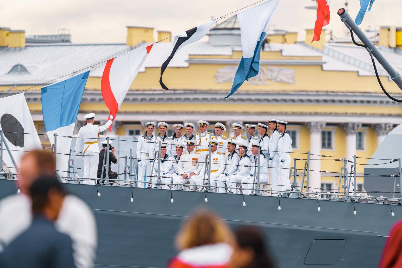 Russia, St. Petersburg, 31 July 2022: Military sailors dressed in festive uniforms take a group photo with the commander on the deck of a warship next to a huge cannon, the celebration the Navy Day. High quality photo