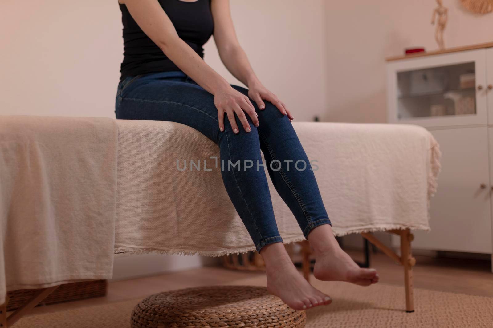 A female patient waits with her legs hanging from the massage table, before her therapist gives her a health treatment