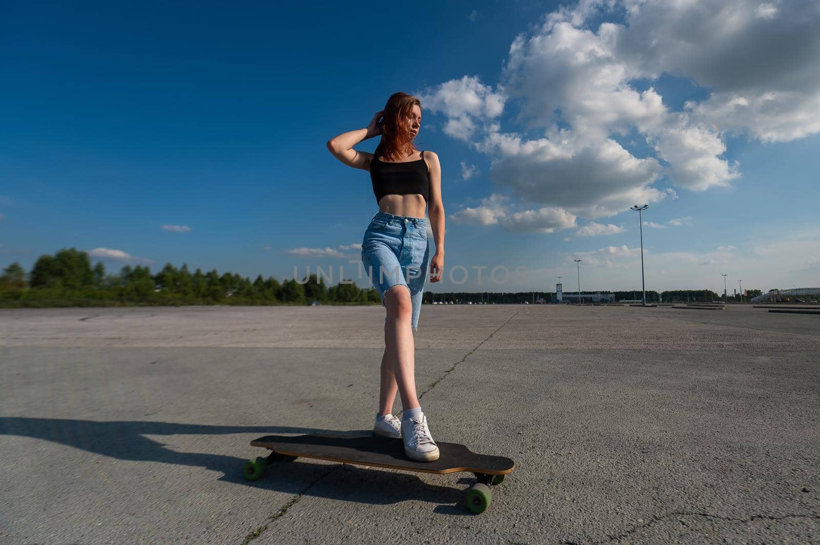 Young caucasian woman riding a longboard outdoors. by mrwed54