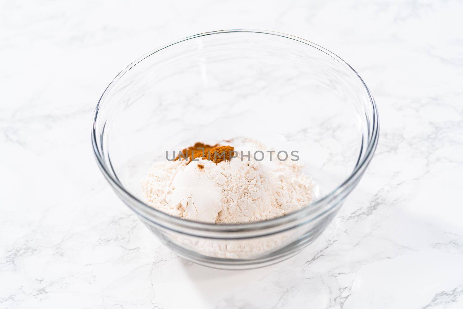 Mixing dry ingredients in a large glass mixing bowl to bake soft oatmeal raisin walnut cookies.