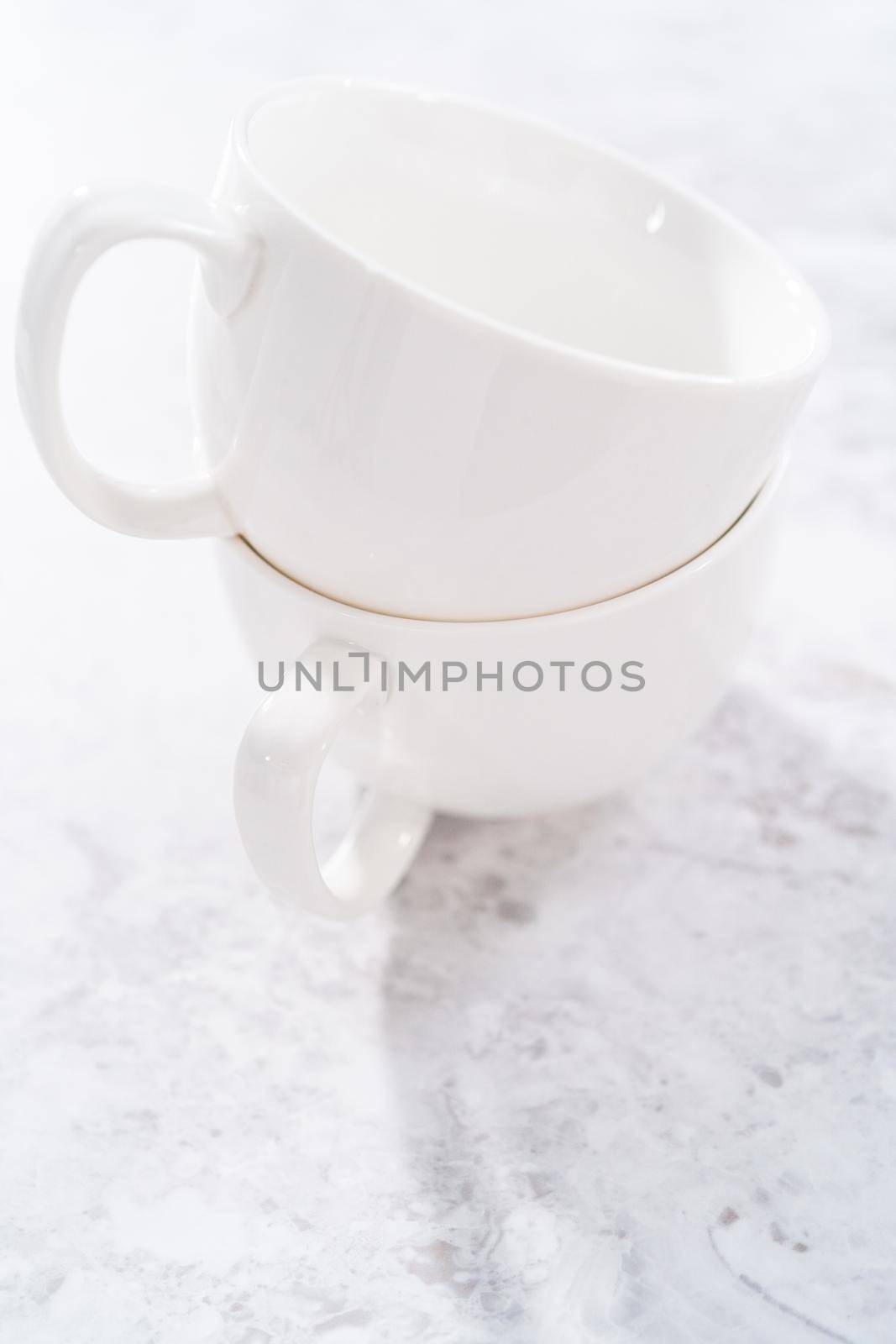 White ceramic cups prepared to bake chocolate mug cakes.