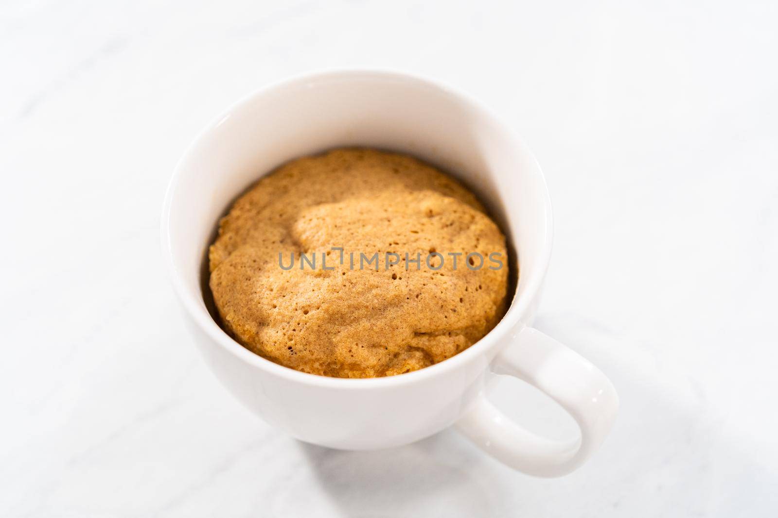 Freshly made to prepare pumpkin mug cake in a large white mug.
