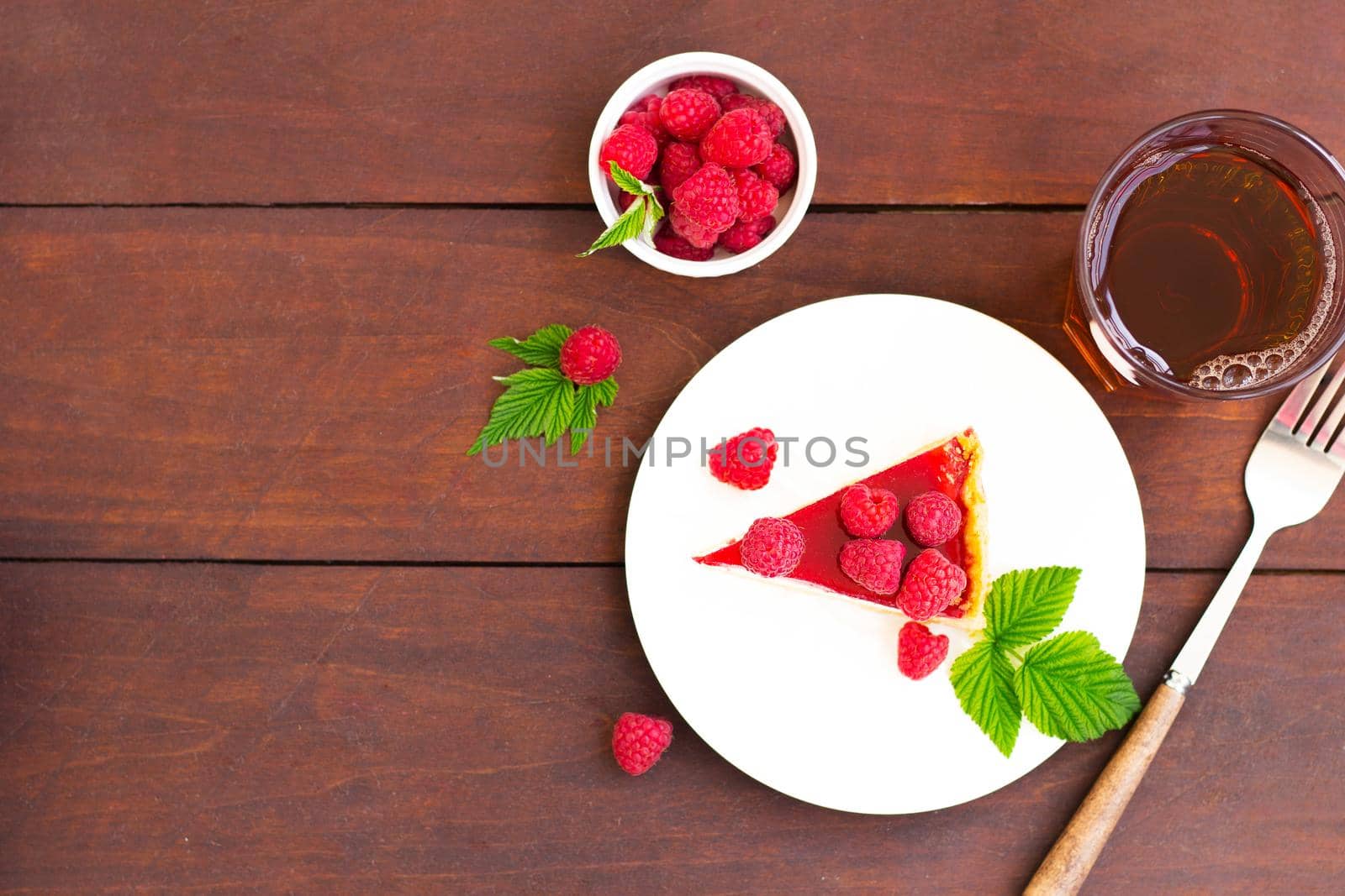 Raspberry pie (cheesecake) made from fresh raspberries with tea on a wooden background.Copy space