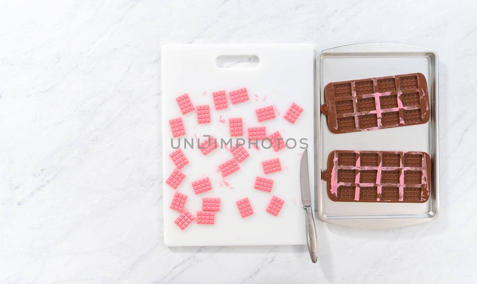 Flat lay. Removing mini pink chocolates from silicone chocolate mold.