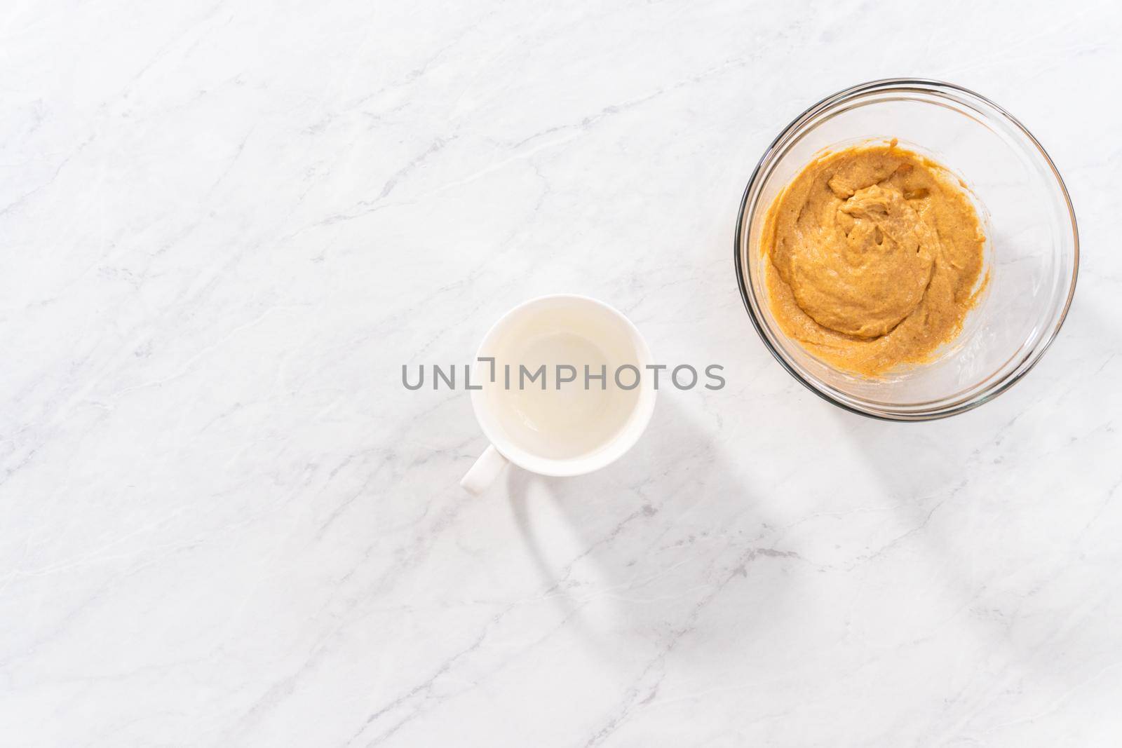 Flat lay. Pouring cake batter into the mug to prepare pumpkin mug cake.