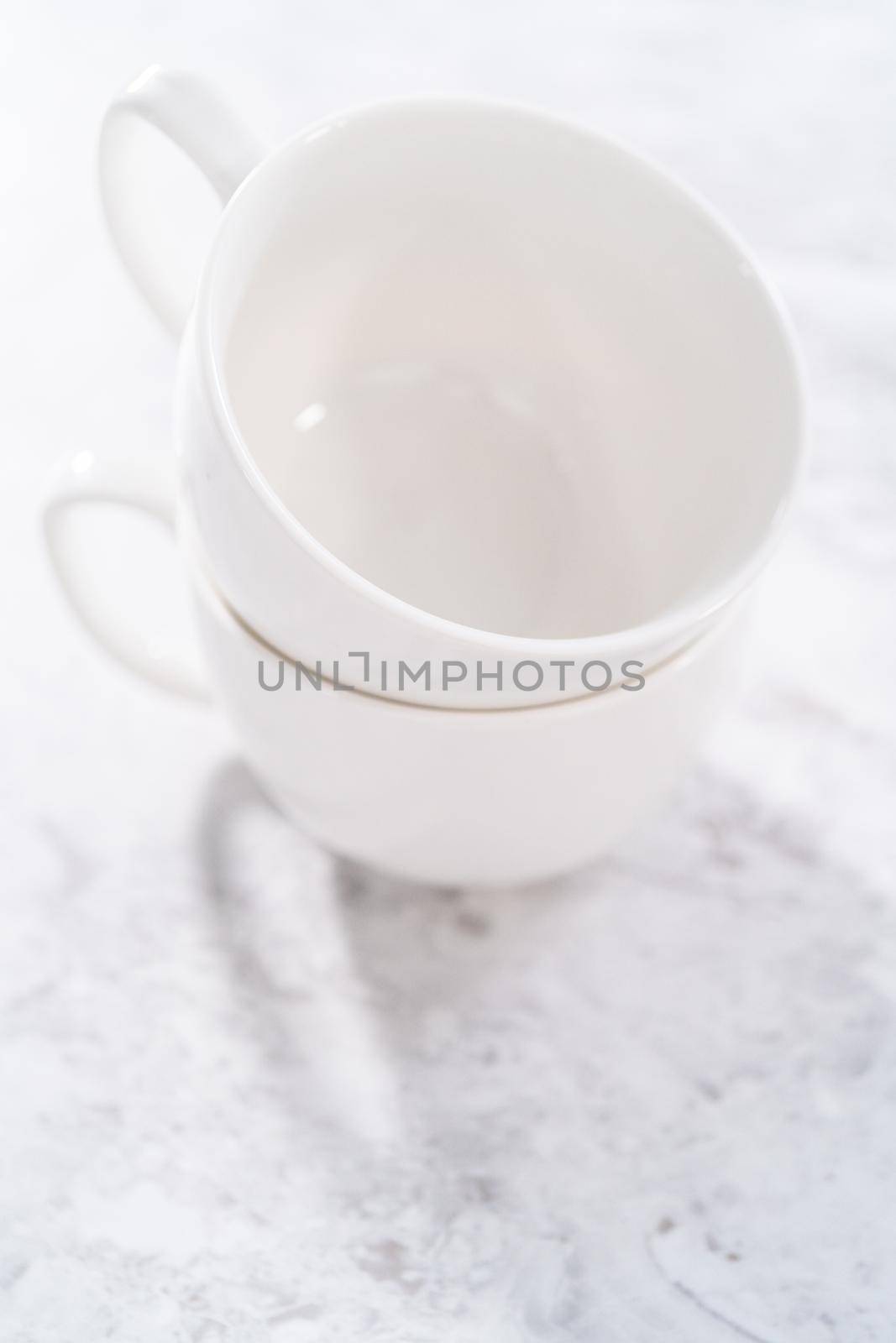 White ceramic cups prepared to bake chocolate mug cakes.