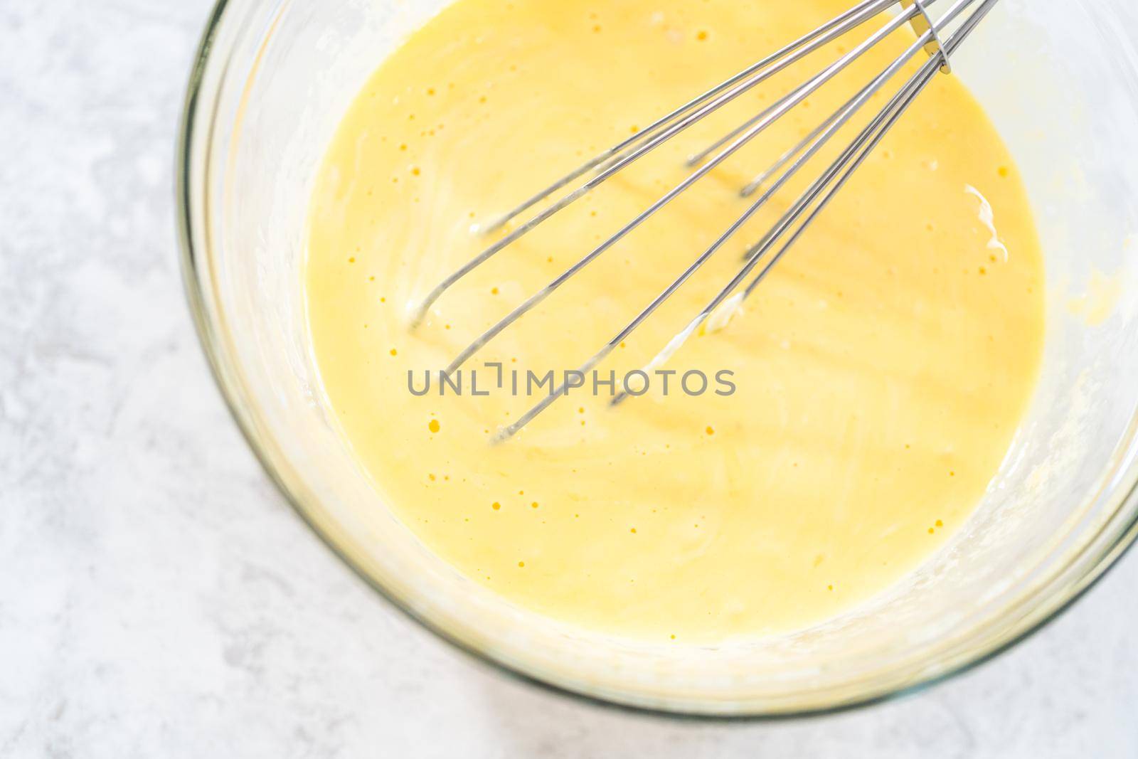 Close up view. Close up view. Mixing ingredients in a glass mixing bowl to bake funfettti bundt cake.