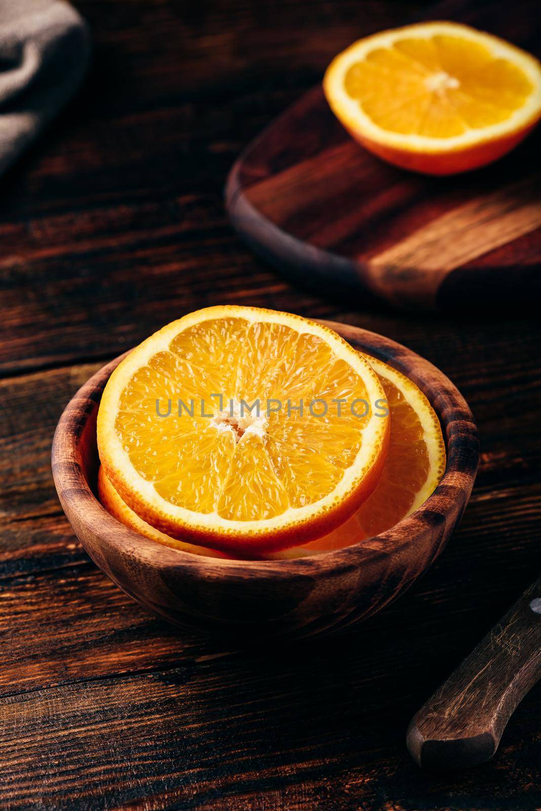 Sliced orange in a wooden bowl in rustic setting