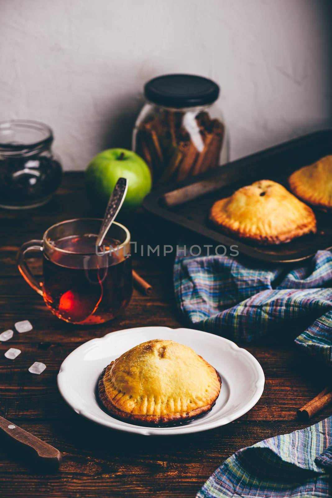 Homemade apple mini pie on white plate with cup of black tea