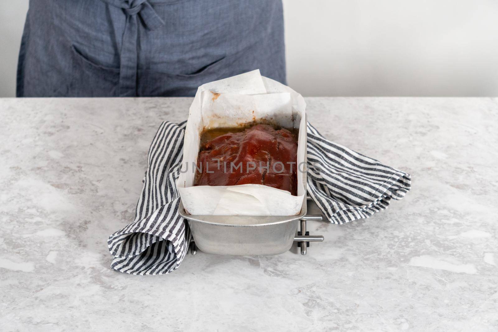 Cooling classic meatloaf glazed with sweet glaze in a loaf pan lined with parchment paper.