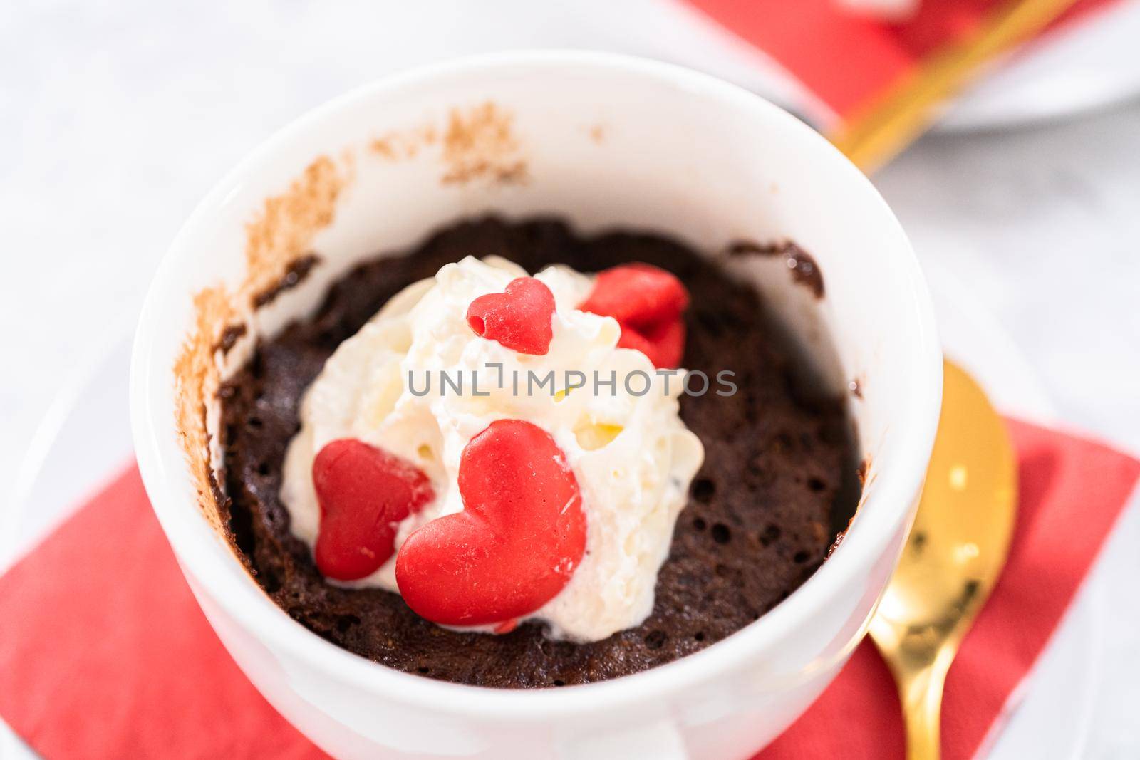 Chocolate mug cakes garnished with whipped cream and chocolate hearts and lips.