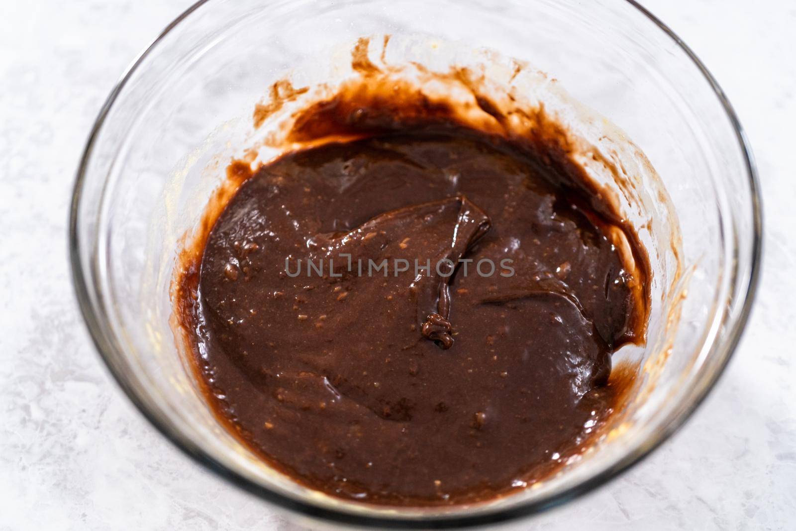 Chocolate cake dough in a glass mixing bowl on the counter.