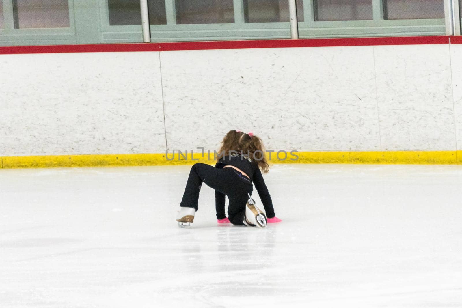 Little girl practicing figure skating moves on the indoor ice rink.