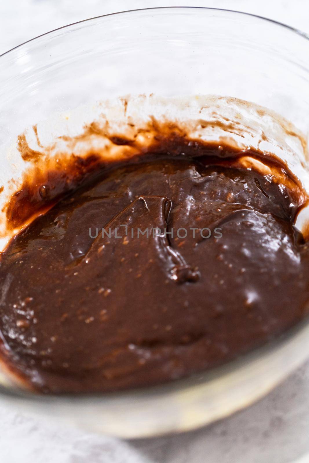 Chocolate cake dough in a glass mixing bowl on the counter.