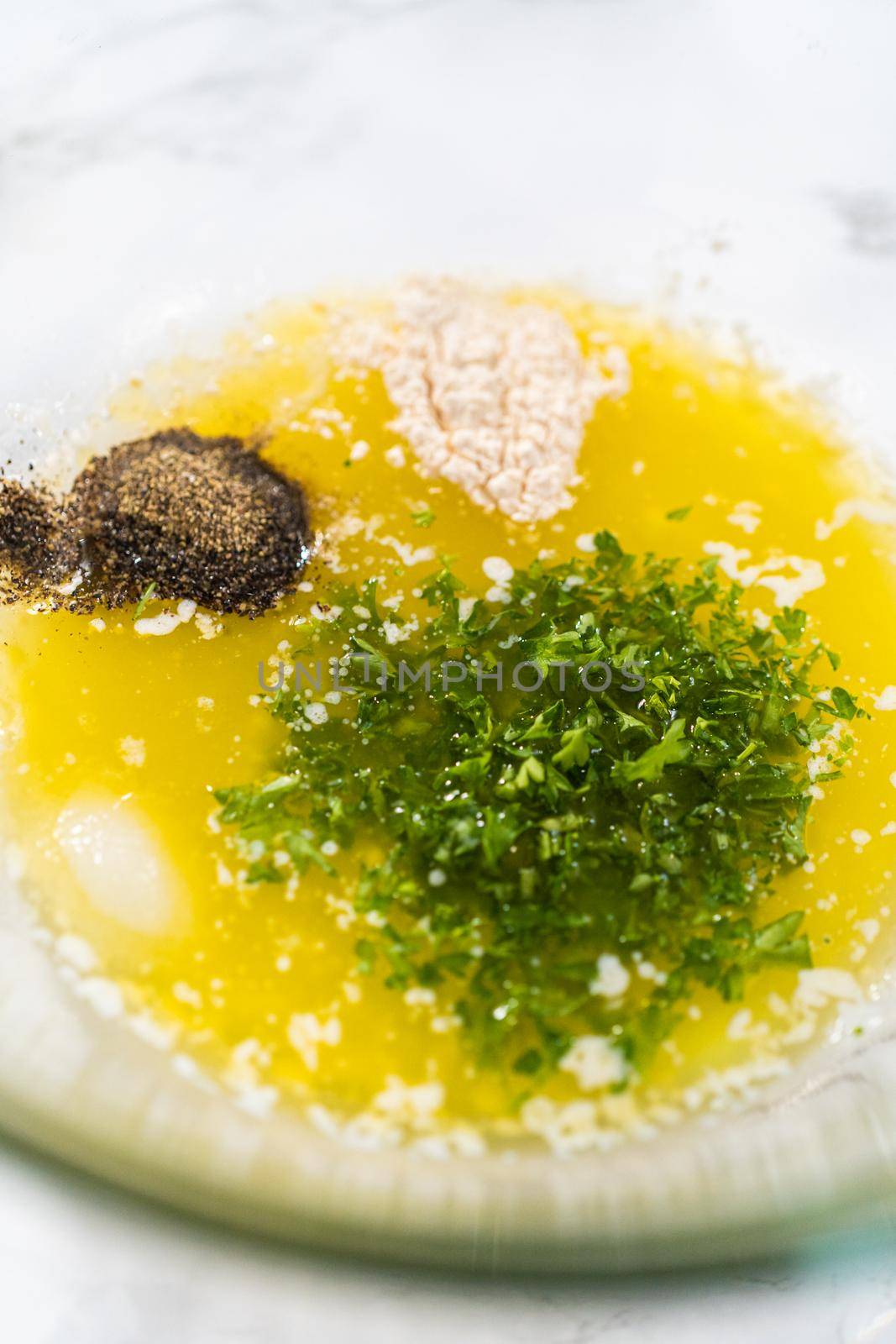 Mixing ingredients in a glass mixing bowl to prepare butter mixture for garlic lobster tails.