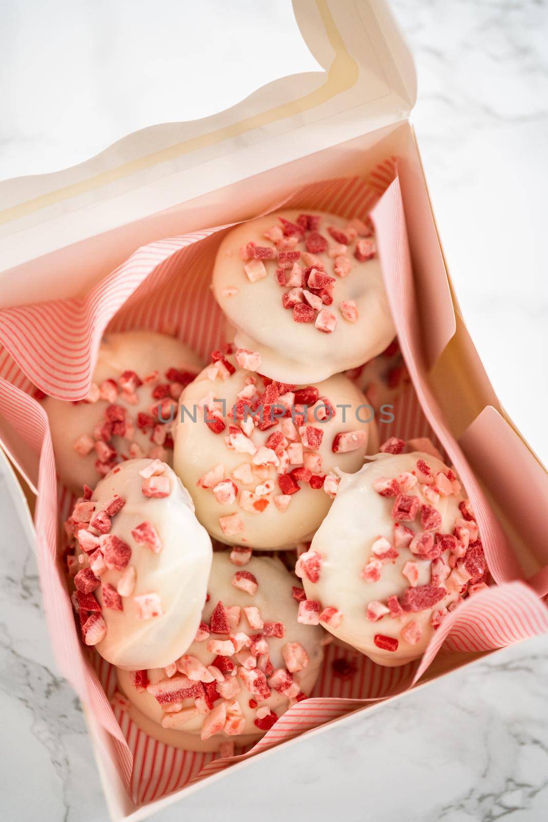 Packing freshly baked peppermint white chocolate cookies into a white paper box.