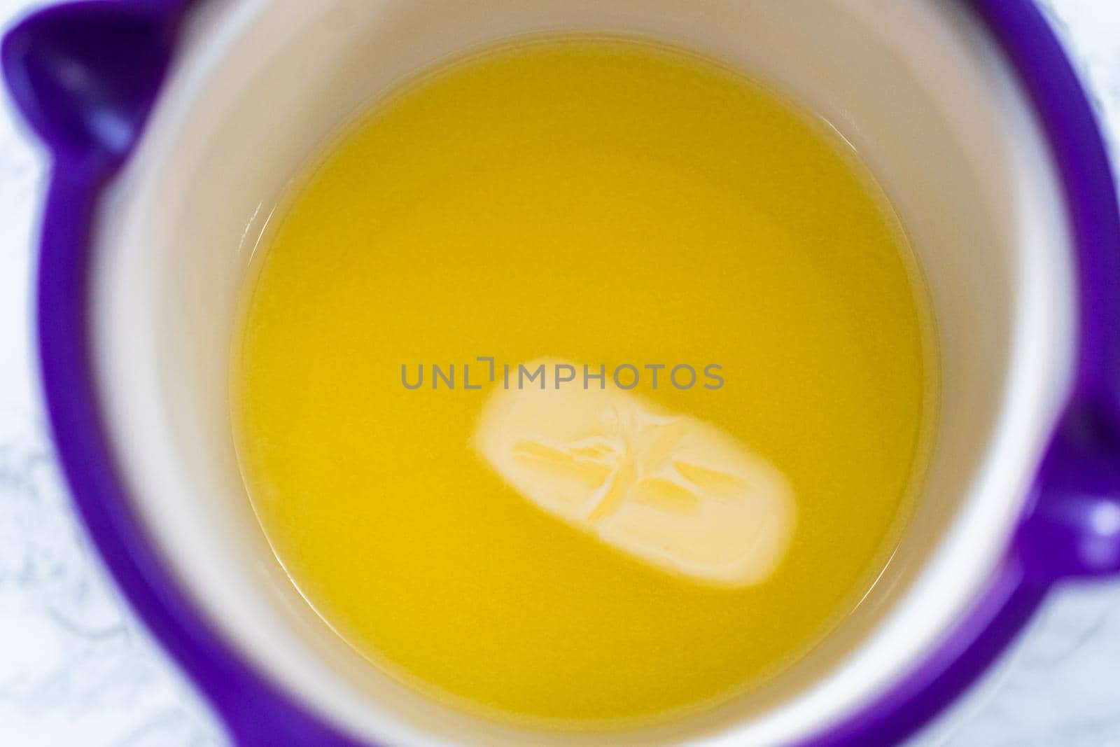 Melting stick of unsalted butter in candy melting pot.