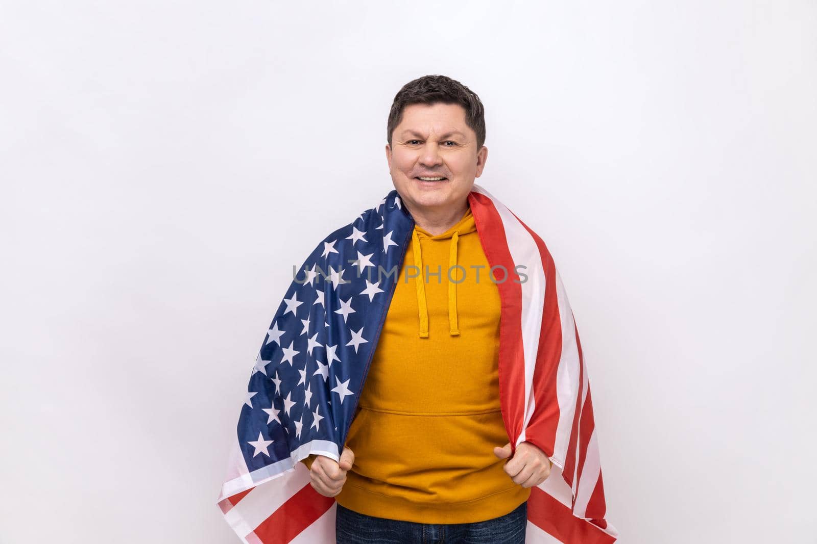 Handsome middle aged man standing wrapped in USA flag, celebrating national holiday. by Khosro1
