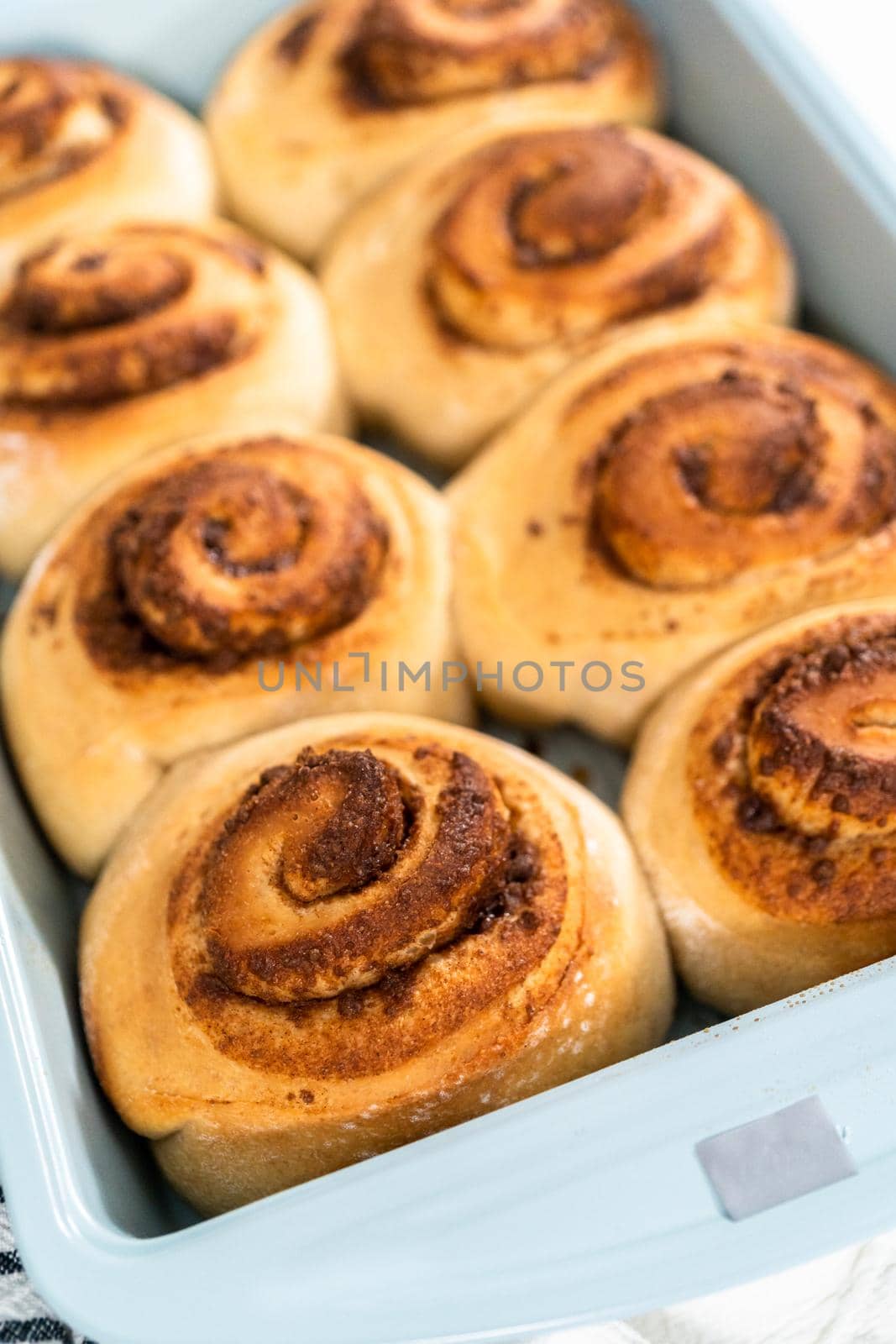 Freshly baked cinnamon rolls in a blue baking pan.